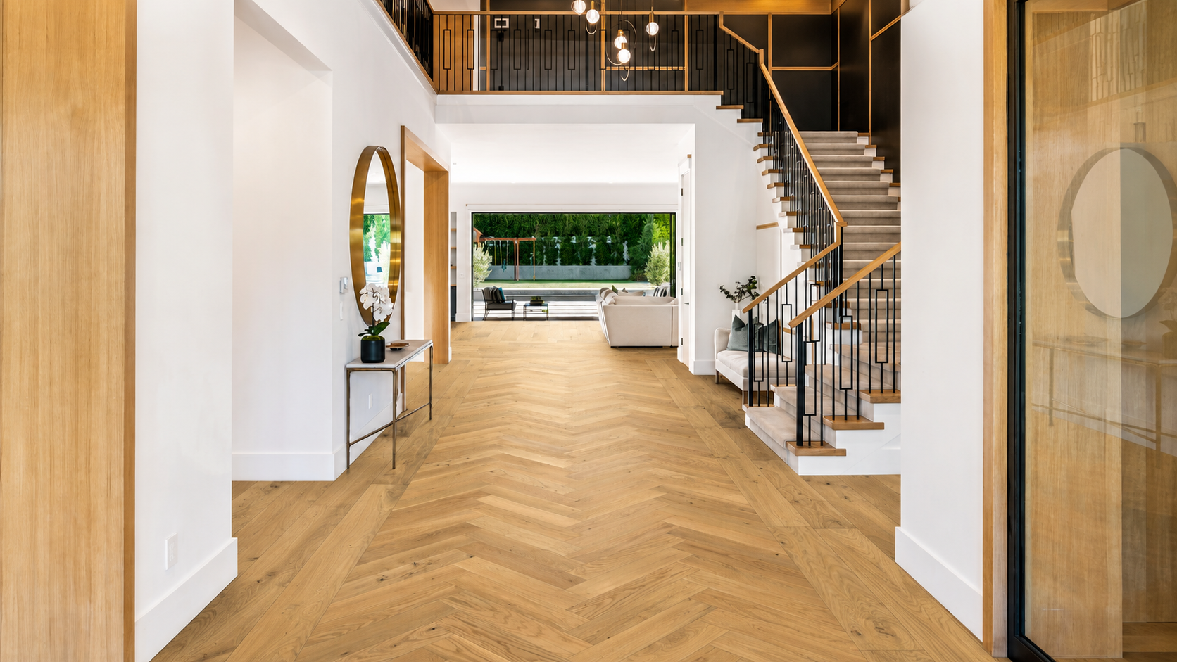 Natural oak herringbone hardwood flooring with a straight border in a bright entry hallway